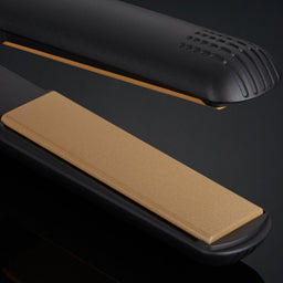 Black hair straightener with beige heating plate on a dark background