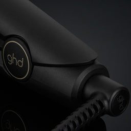 Black hair straightener with 'ghd' branding on a dark background