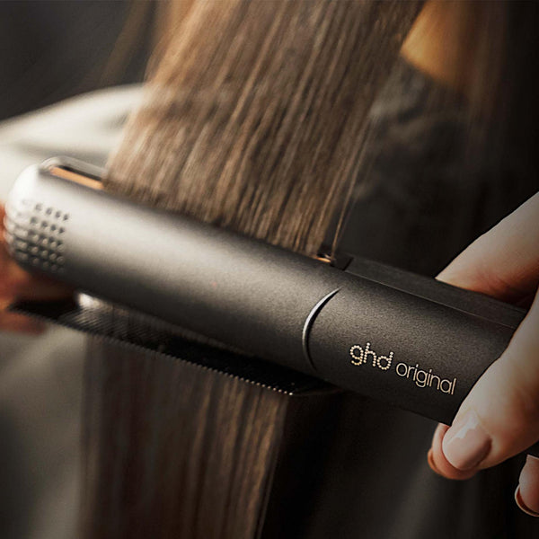 Person using a ghd hair straightener on their hair