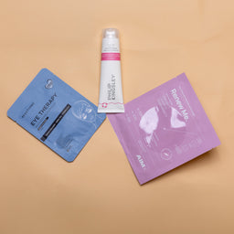 Skincare products including a tube and two packets on a beige background