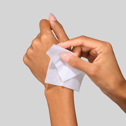 Hands holding a small white square of paper against a light gray background