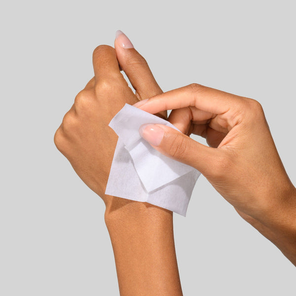 Hands holding a small white square of paper against a light gray background