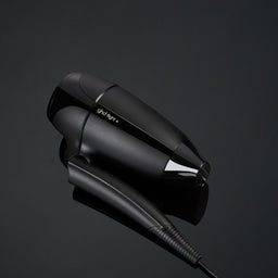 Black hair dryer on a reflective black surface with a dark background