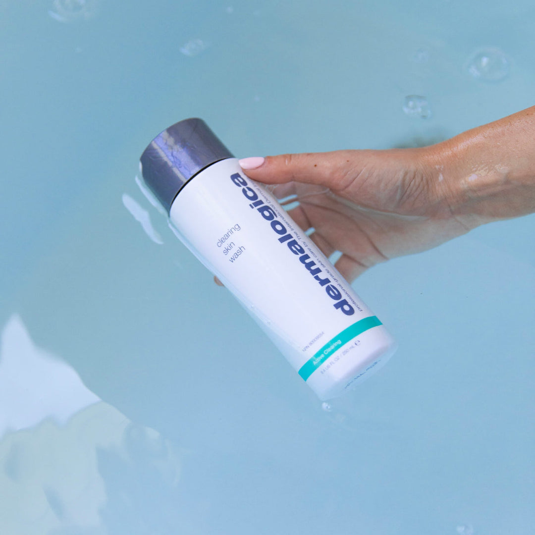 Hand holding a DermaEgo skincare product against a light blue background