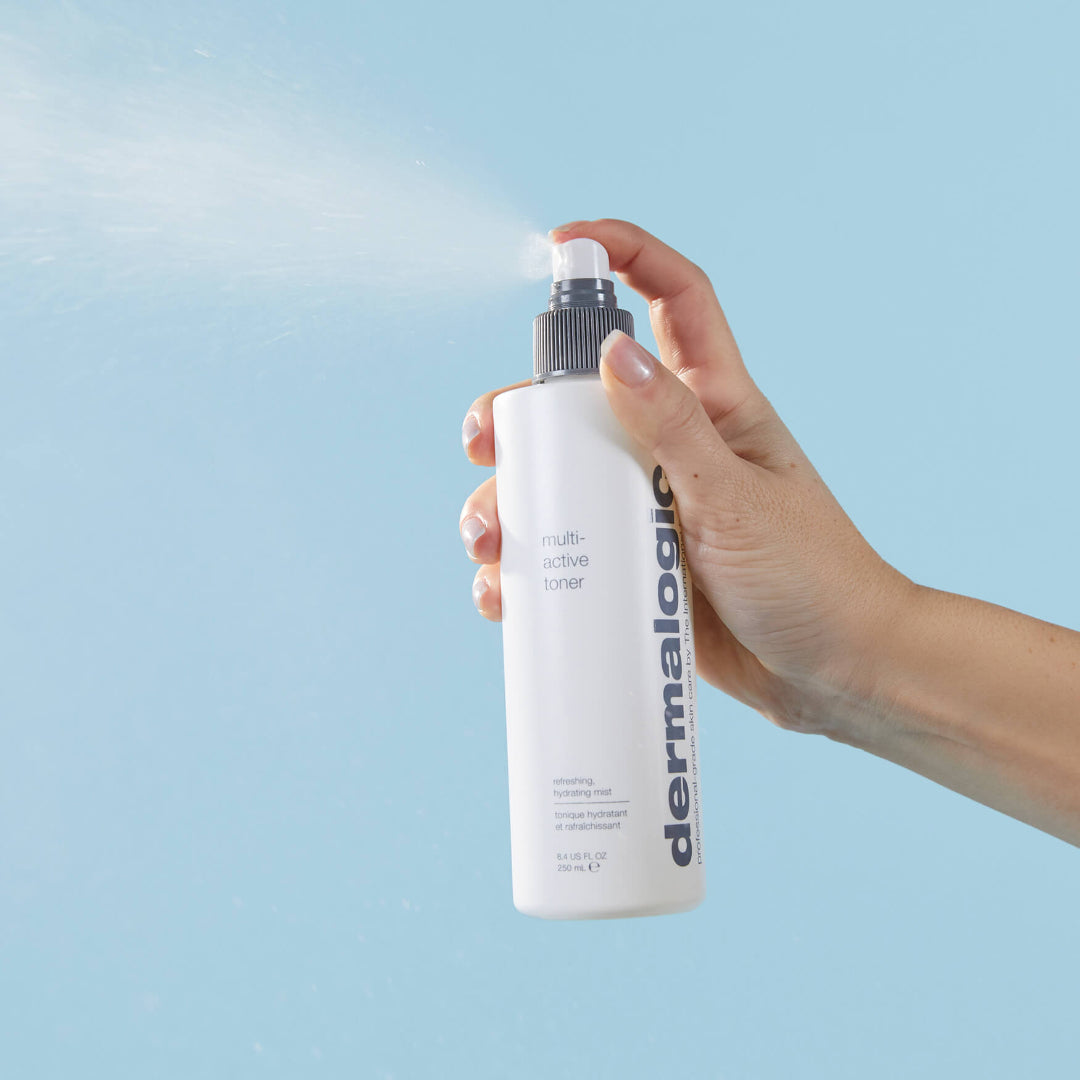 Hand holding a Dermalogica toner bottle against a light blue background