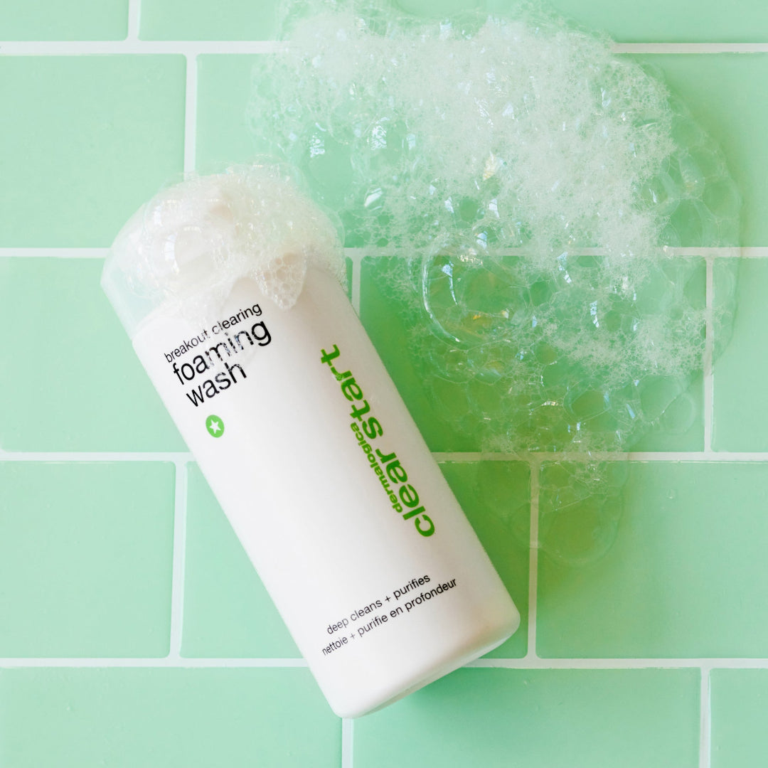 Foaming wash bottle with bubbles on a green tiled background