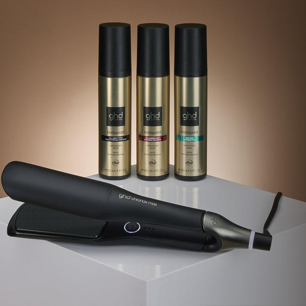 Hair straightener and three bottles on a white platform with a brown gradient background