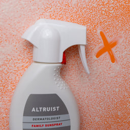 Spray bottle labeled 'Altruist' on a textured orange background