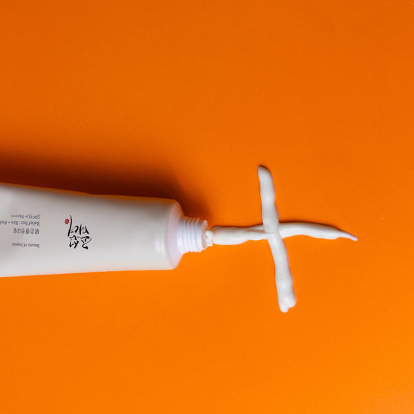 Tube of cream with a white applicator on an orange background