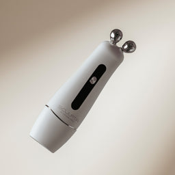 White handheld device with two metallic probes on a beige background