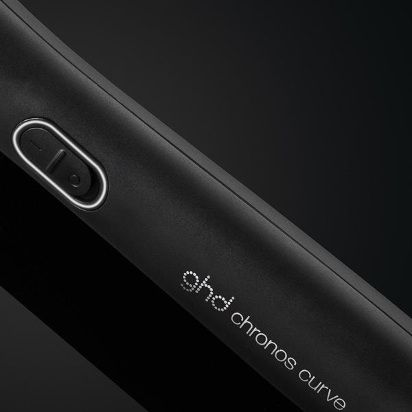 Close-up of a black device with 'ghd chronos curve' branding on a dark background