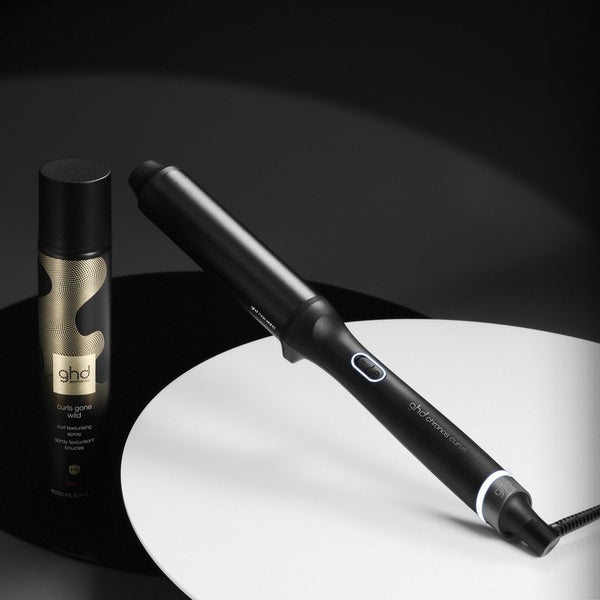 Hair straightener and bottle on a dark background