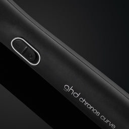 Close-up of a black device with 'ghd chronos curve' branding on a dark background
