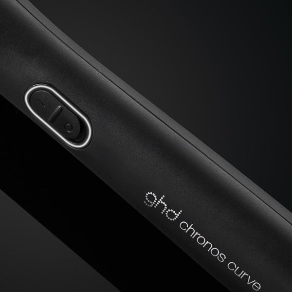 Close-up of a black device with 'ghd chronos curve' branding on a dark background