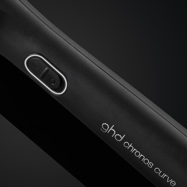 Close-up of a black device with 'ghd chronos curve' branding on a dark background