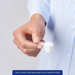 A close-up of a person's hand holding a small white scoop filled with white powder, wearing a light blue and white striped shirt. A blue text banner at the bottom reads, 'TAKE 1 SCOOP TWICE DAILY MIXED IN WITH WATER OR JUICE'.