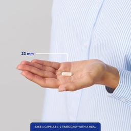 Hand holding a capsule with measurement label and text on a plain background