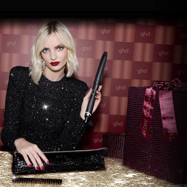 Woman holding a ghd hair straightener with branded background