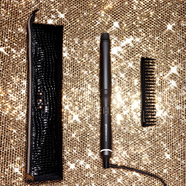 Makeup tools including a brush, eyeliner, and mascara on a glittery surface