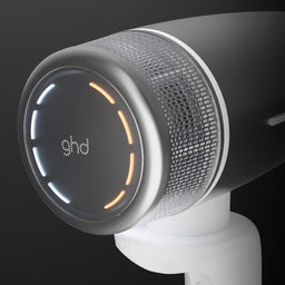 White hair dryer with 'ghd' branding on a black background