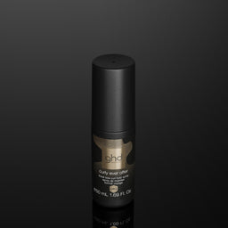 A single black cylindrical cosmetic bottle with a metallic gold label reading 'ghd' and 'Super Smooth Hair Smoother' on a dark reflective black background.