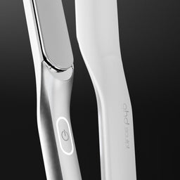 Close-up of a sleek white hair straightener with a metallic silver edge and a power button, set against a dark gradient background. The brand name 'hair of my life' is printed vertically on the handle.