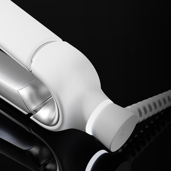 A close-up of a white and silver hair straightener, shown partially cropped against a dark black background.