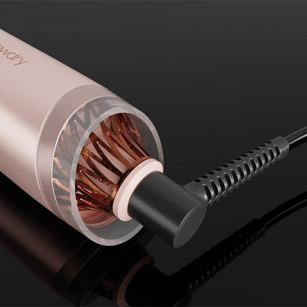 A close-up of a hair styling tool with a metallic rose gold body, showing the copper heating plates inside the barrel and a black cord plugged in on a glossy black background.