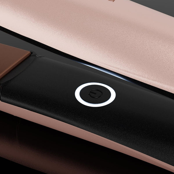 Close-up of a hair straightener showing its rose gold metallic exterior, black interior plate, and a circular power button.