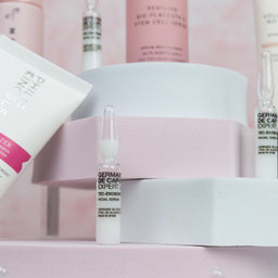 Collection of skincare products on a pink background