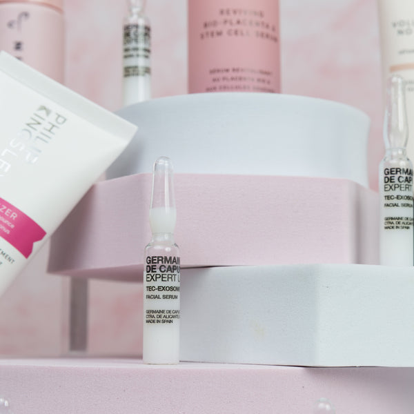 Collection of skincare products on a pink background