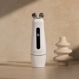 White handheld device with silver knobs on a beige surface