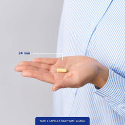 Hand holding a capsule with measurement label and text on a plain background