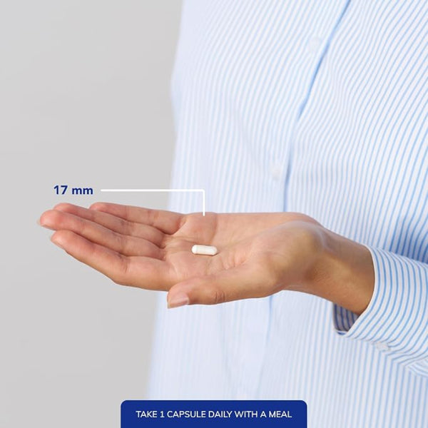A person in a blue and white striped shirt holds an open hand showing a single white capsule pill, with a measurement label indicating 17 mm and a text note at the bottom saying to take 1 capsule daily with a meal.