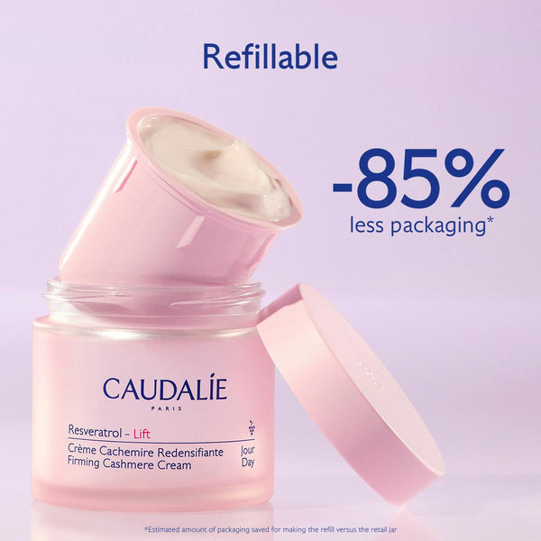 Caudalé Paris Resveratrol Lift Firming Cashmere Cream in a pink jar with the lid off, showing the cream inside. The image includes promotional text reading 'Refillable' and '-85% less packaging' on a light lavender background.