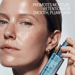 Person holding a skincare product with text about moisture retention on a plain background