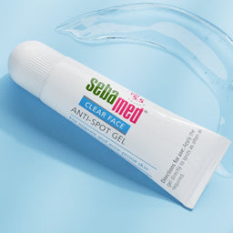 A white squeeze tube of Salimind mouthwash with colorful text, resting on a light blue background with a clear liquid splash effect.