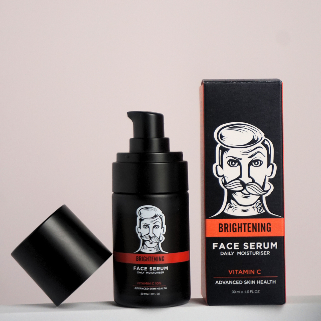 Black face serum bottle with pump and packaging on a light gray background