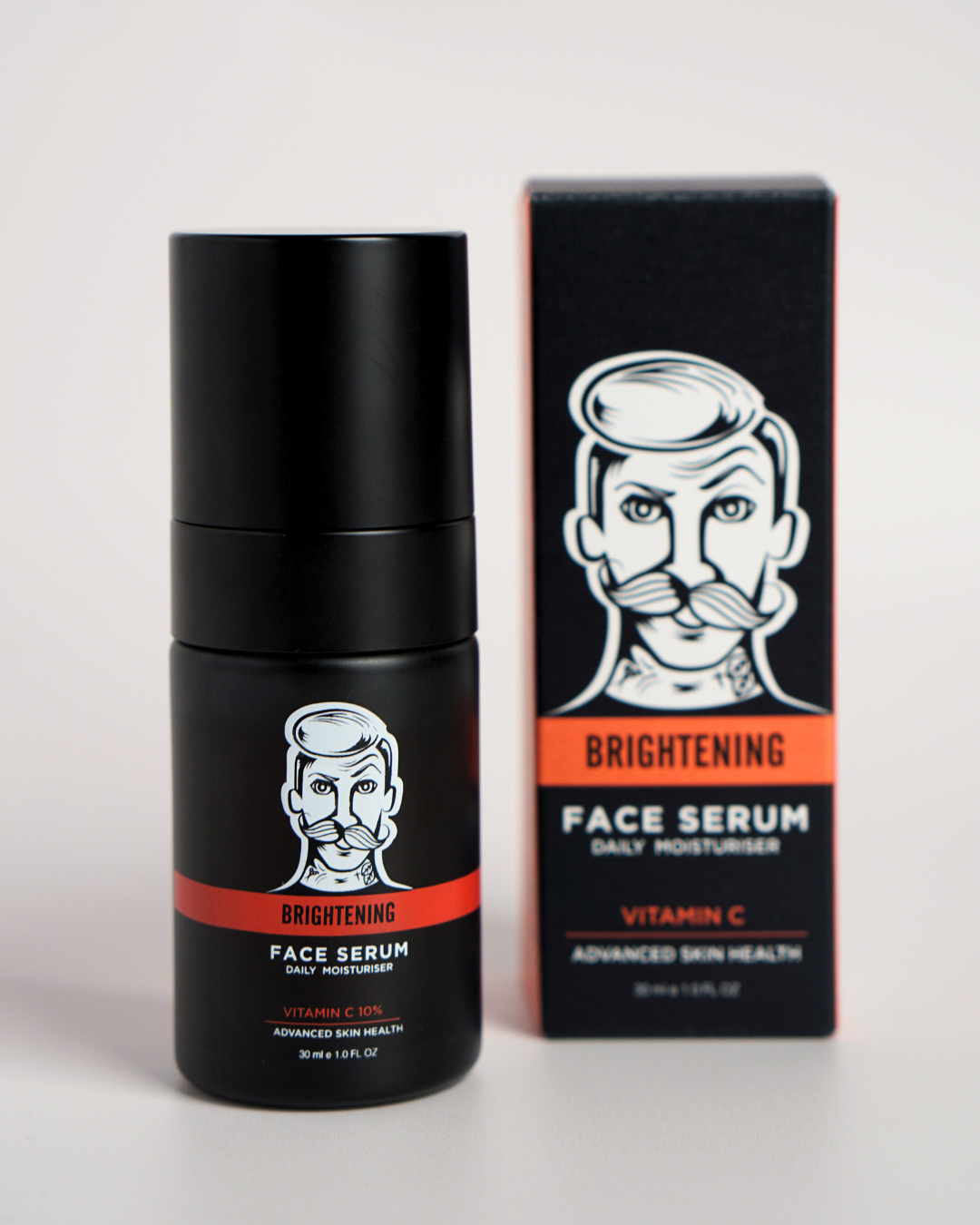 Black face serum bottle with red label and matching box on a light gray background