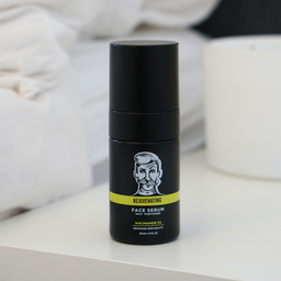 Black face serum bottle with a label on a white surface