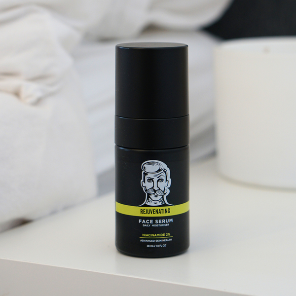 Black face serum bottle with a label on a white surface