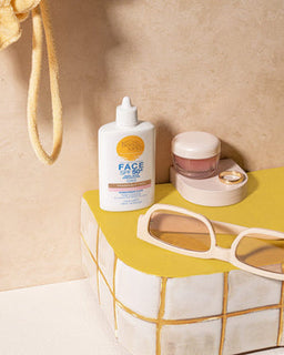 Bondi Sands SPF 50+ Fragrance Free Tinted Face Fluid bottle next to a set of sunglaases