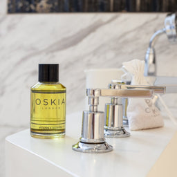 OSKIA Vitamin E Bath Oil bottle on a bathroom countertop