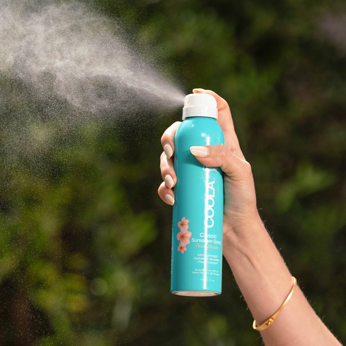 Model spraying COOLA Body Spray SPF30 177ml