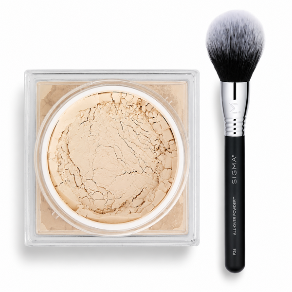 Sigma All-Over Power Pressed Powder in a clear square compact next to a black and silver makeup brush on a white background.