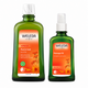 Two green Weleda bottles on a white background: a larger Muscle Soak bath milk bottle and a smaller Massage Oil bottle, both with orange labels and white caps.