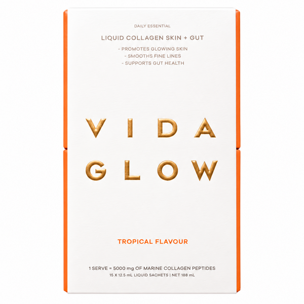 A tall rectangular box of VIDA GLOW Liquid Collagen Skin + Gut in Tropical Flavour, featuring a white front with gold foil lettering and orange side borders on a white background.