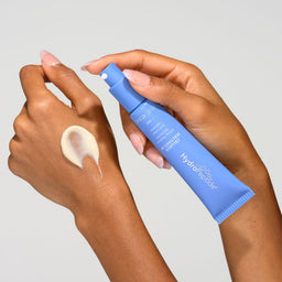 Hand holding a blue skincare product with a white background