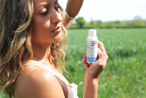 a woman holding a bottle of Proto-col Collagen Shot Red Berry#