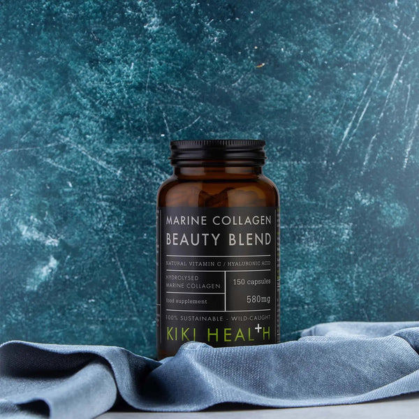 Brown supplement bottle labeled 'Marine Collagen Beauty Blend' by Kiki Health on a blue textured background.